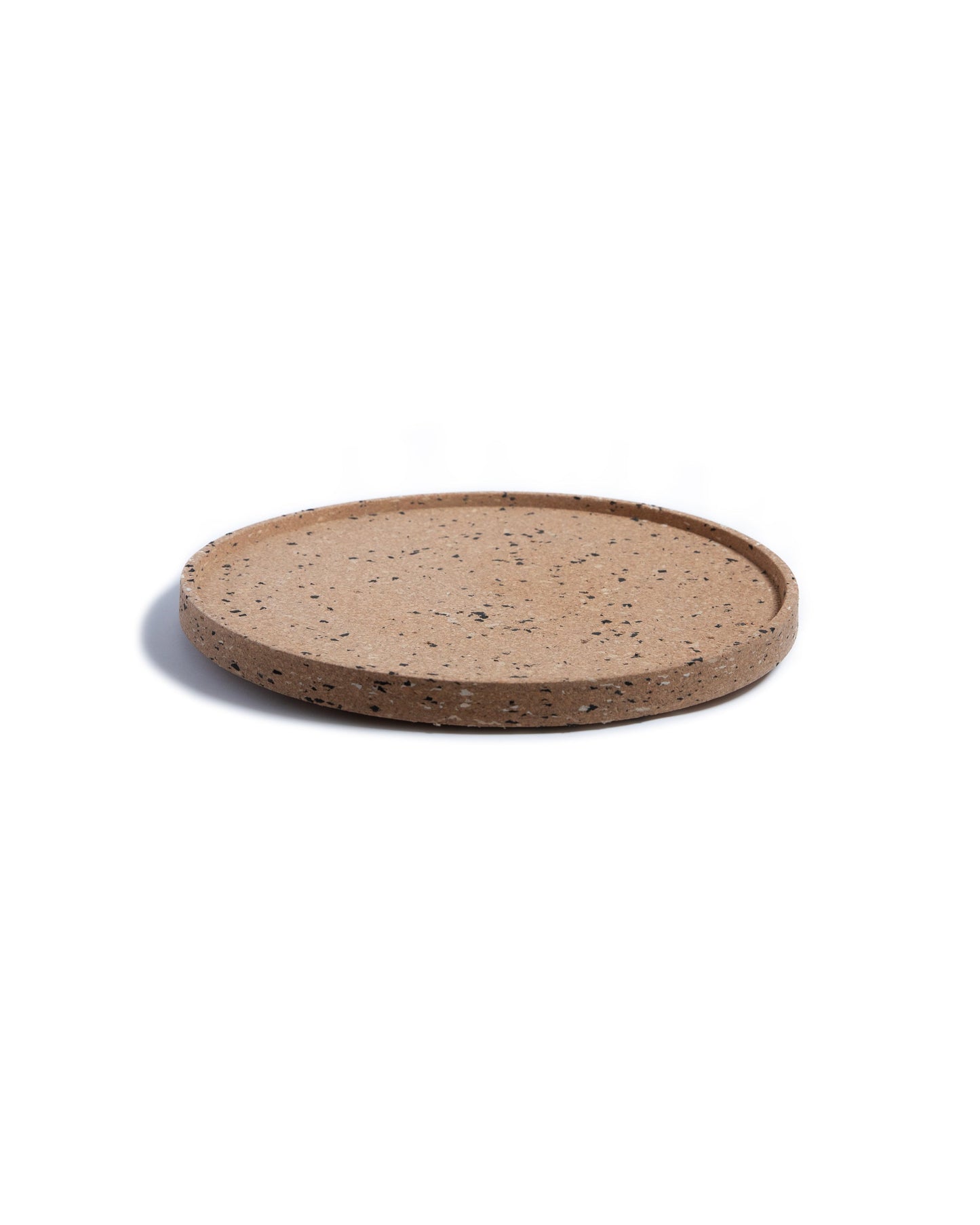 Side view of round cork serving tray with black and grey confetti bits of recycled plastic.