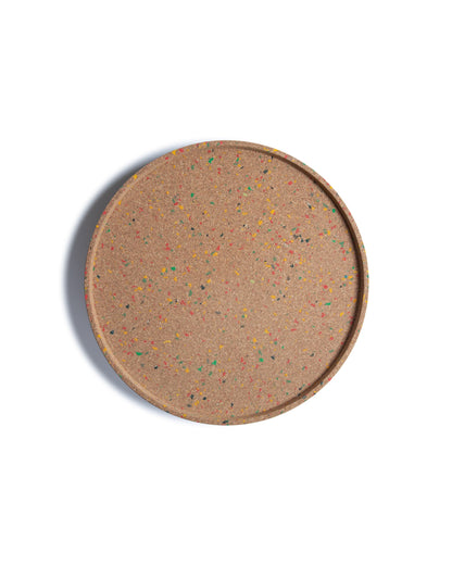 Top view of round cork serving tray with confetti bits of colored recycled plastic.