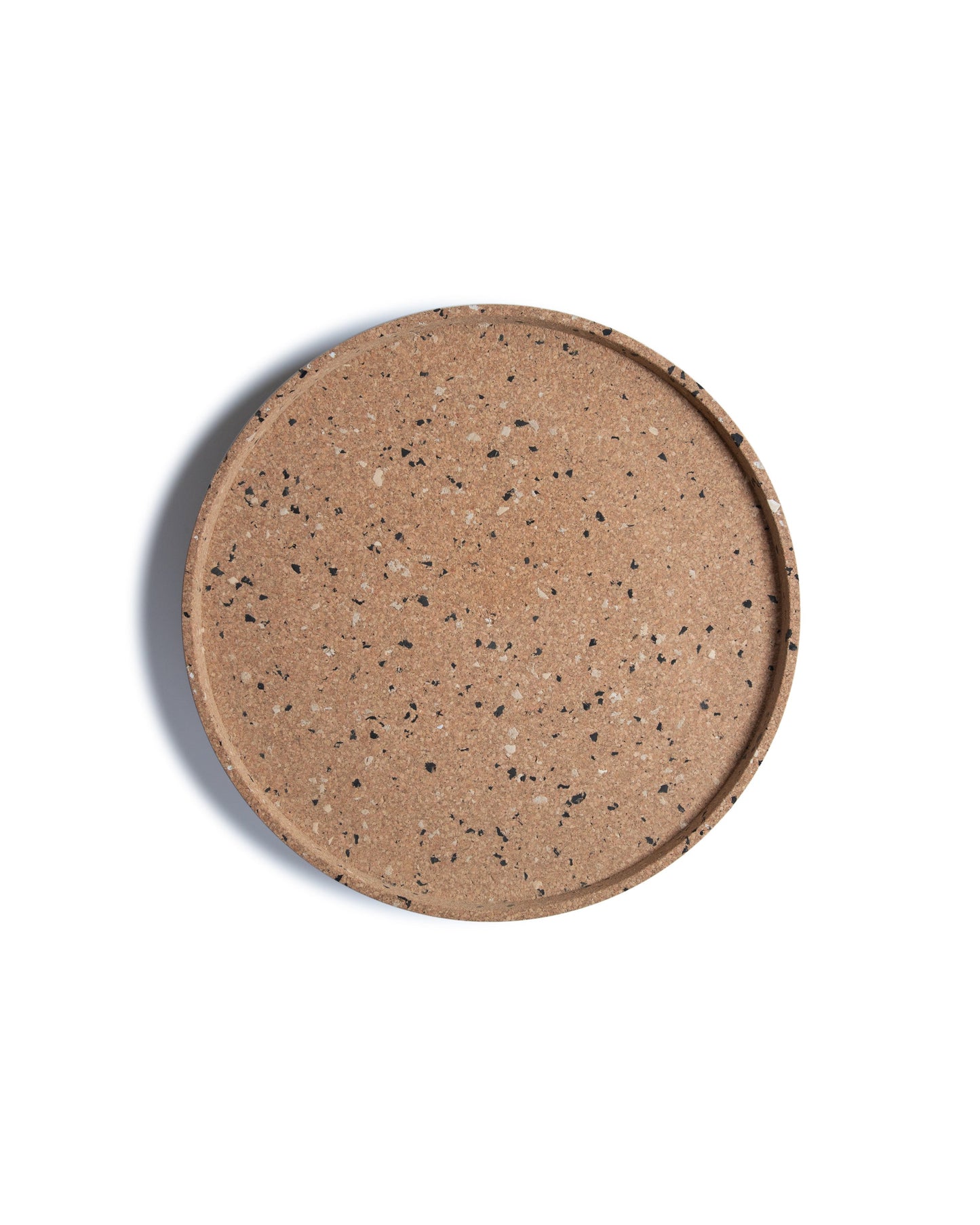 Top view of round cork serving tray with black and grey confetti bits recycled plastic.