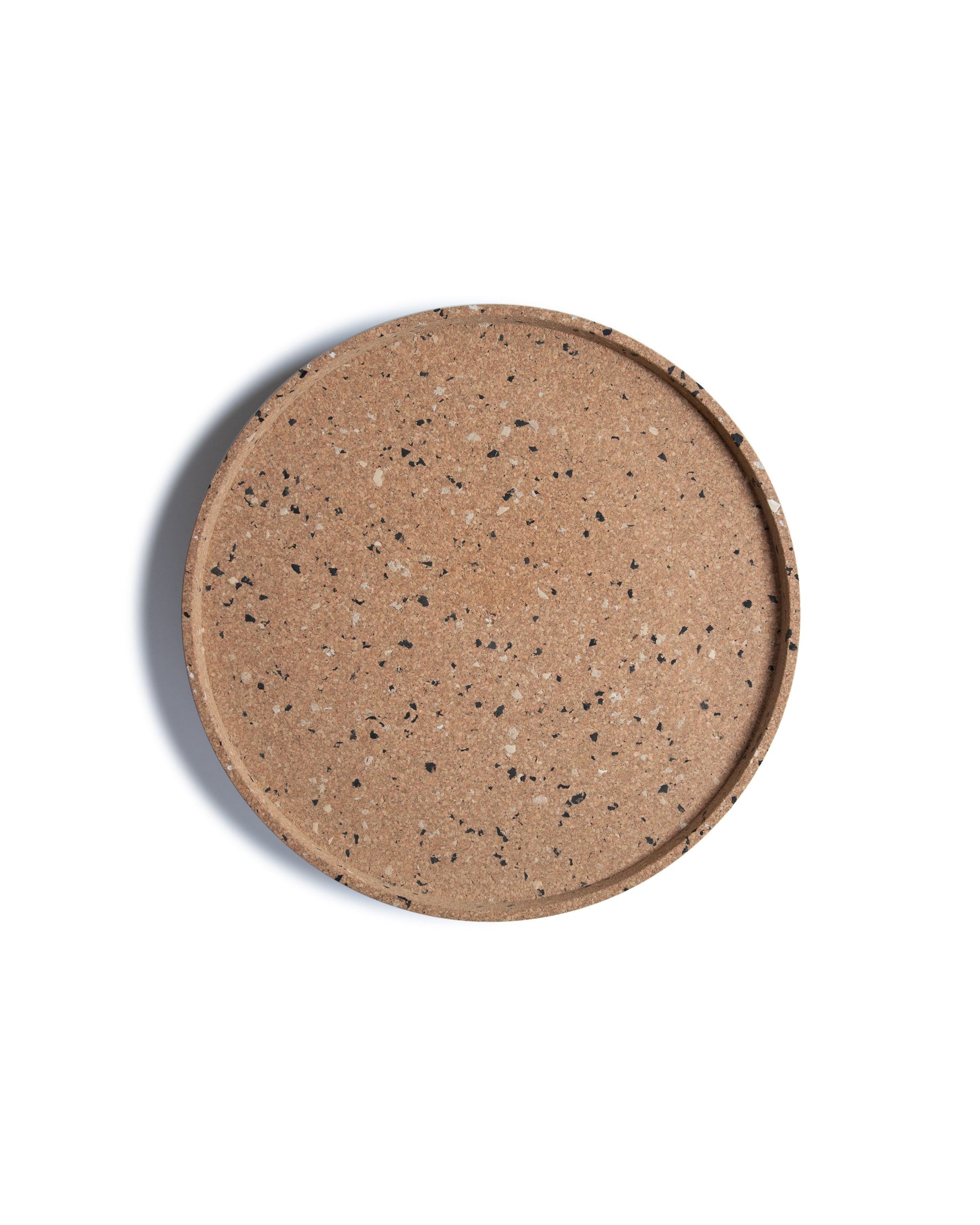 Top view of round cork serving tray with black and grey confetti bits recycled plastic.