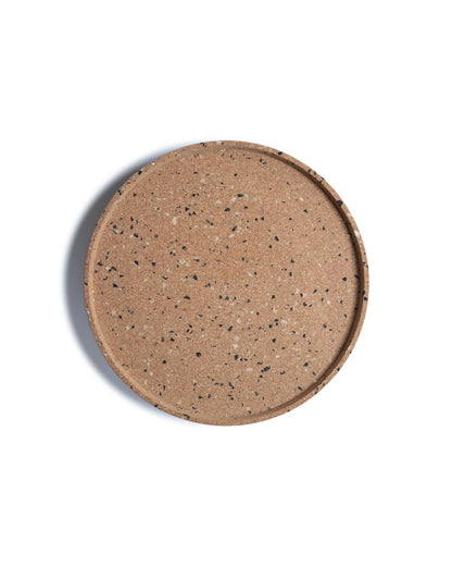 Top view of round cork serving tray with black and grey confetti bits recycled plastic.