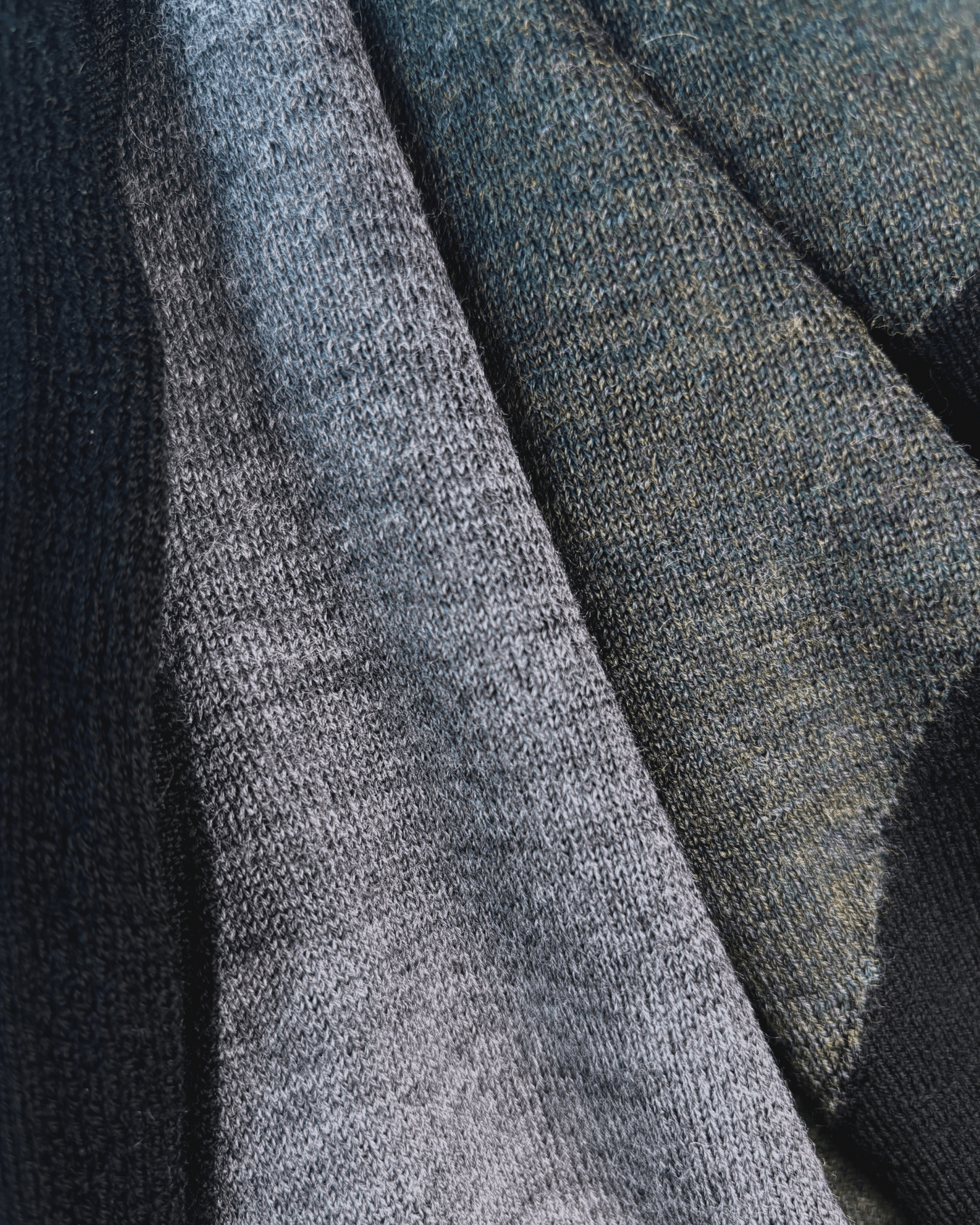 Close Up black, grey, and moss colors of square merino wool scarf.