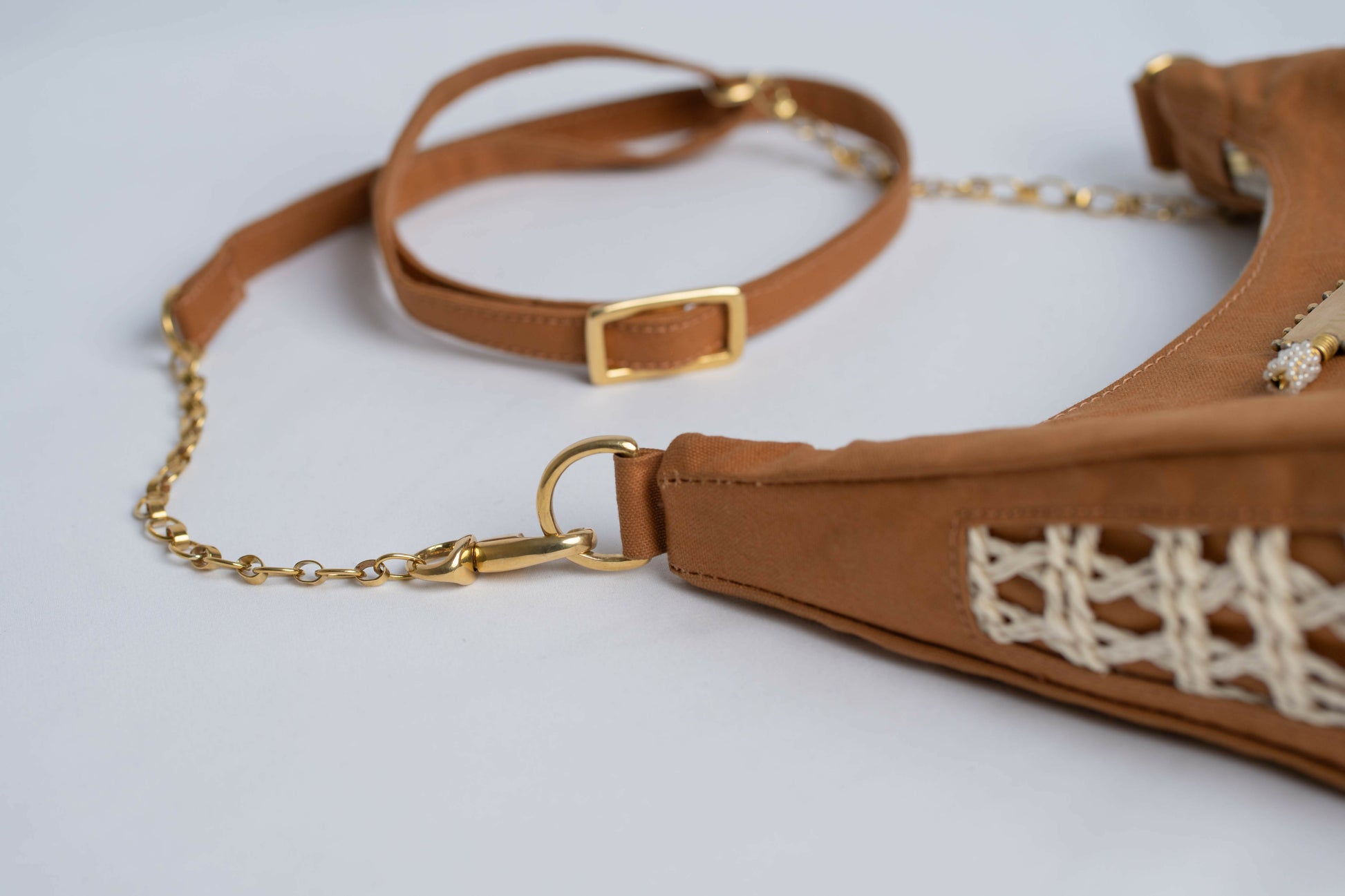Closeup of brown leather handbag with woven sisal sides, chain and leather strap.