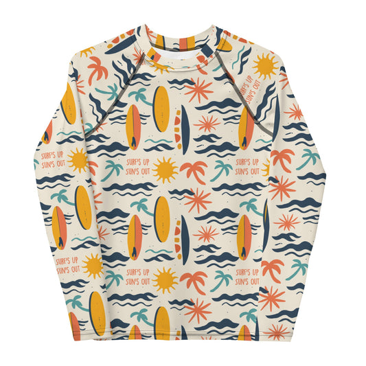 A bold rash guard with a "Surf’s Up" theme, featuring wave patterns and surfboards, shown flat from the front.