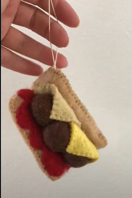 Close up of felt ornament of a meatball sub sandwich.