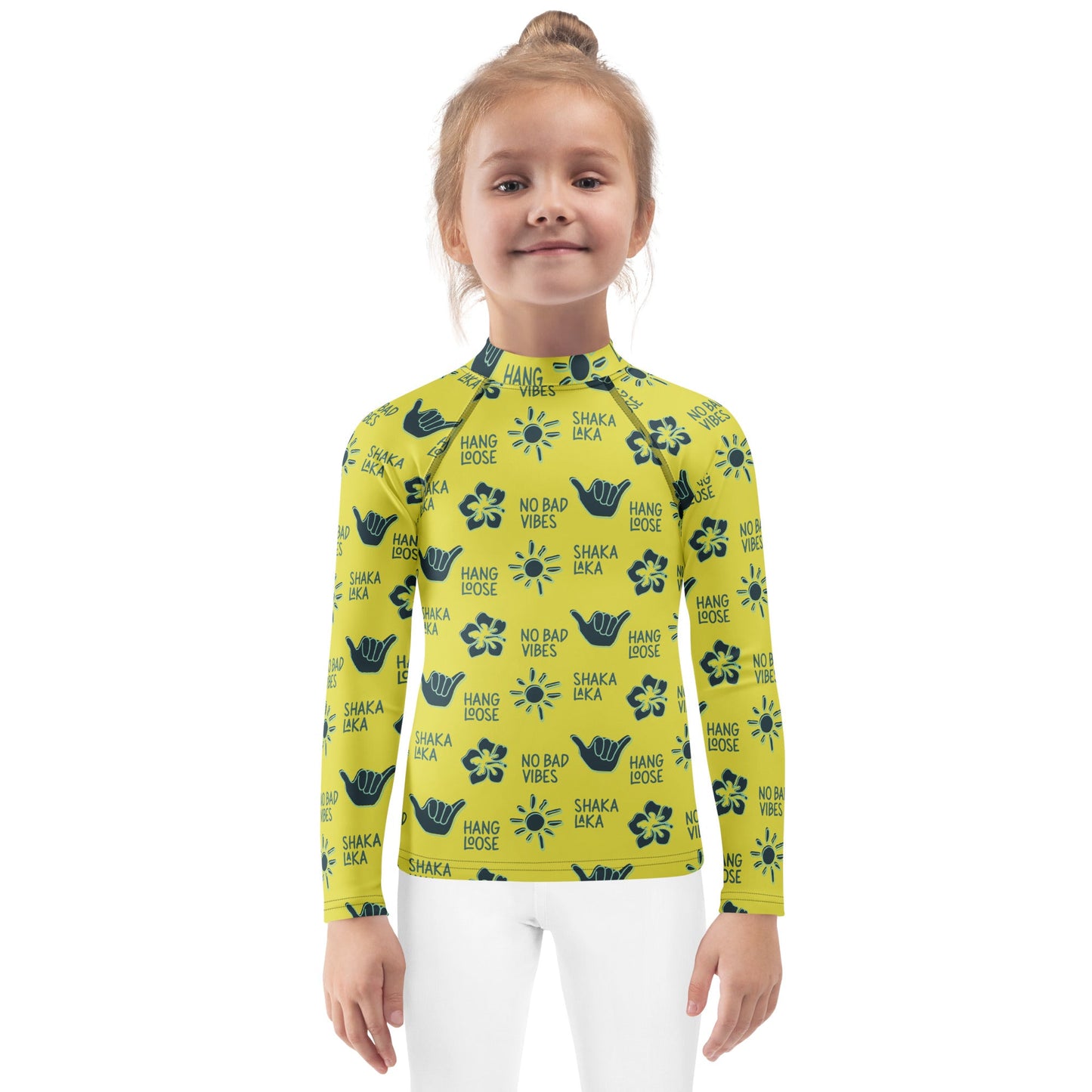 Little girl wearing a yellow rash guard with navy designs of the  sun, hibiscus flowers, hang loose hand sign, and the words hang loose, no bad vibes, and shaka laka.