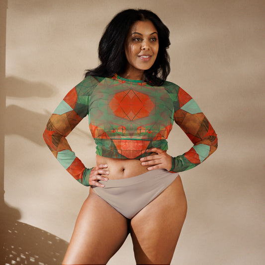 Woman standing with hands on hips in green and orange geometric print cropped rash guard and tan bikini bottoms.