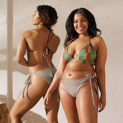 Front and back view of women wearing light and dark green colored print bikini top with orange flowers and light mocha bottoms.