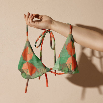 Hand holding up green and orange geometric print bikini top.