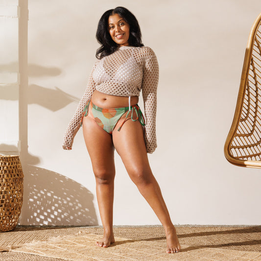 Woman wearing light and dark green with orange flowers print bikini with natural mesh top coverup.