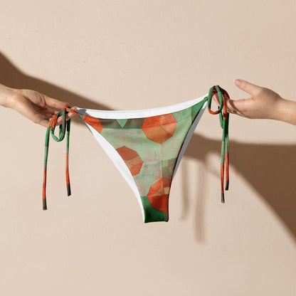 Two hands holding light and dark green with orange flowers print bikini bottoms.