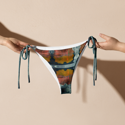 Hands holding up orange and dark blue print bikini bottom.