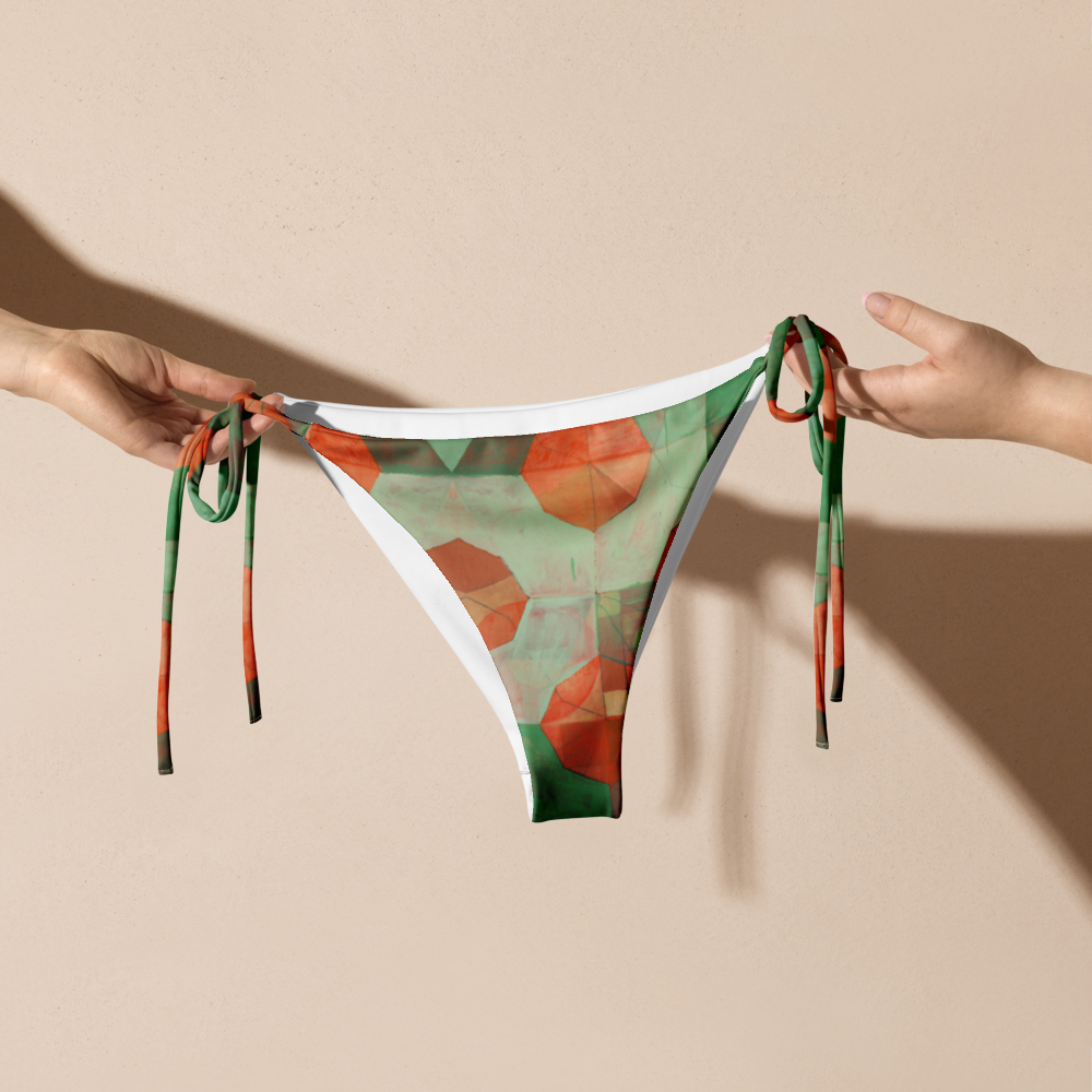 Hands holding up green and orange geometric print bikini bottom.
