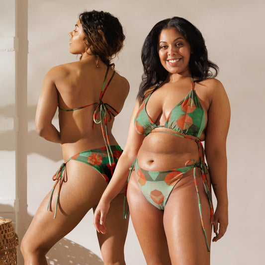 Front and back view of two women wearing light and dark green colored print bikini with orange geometrical flowers.