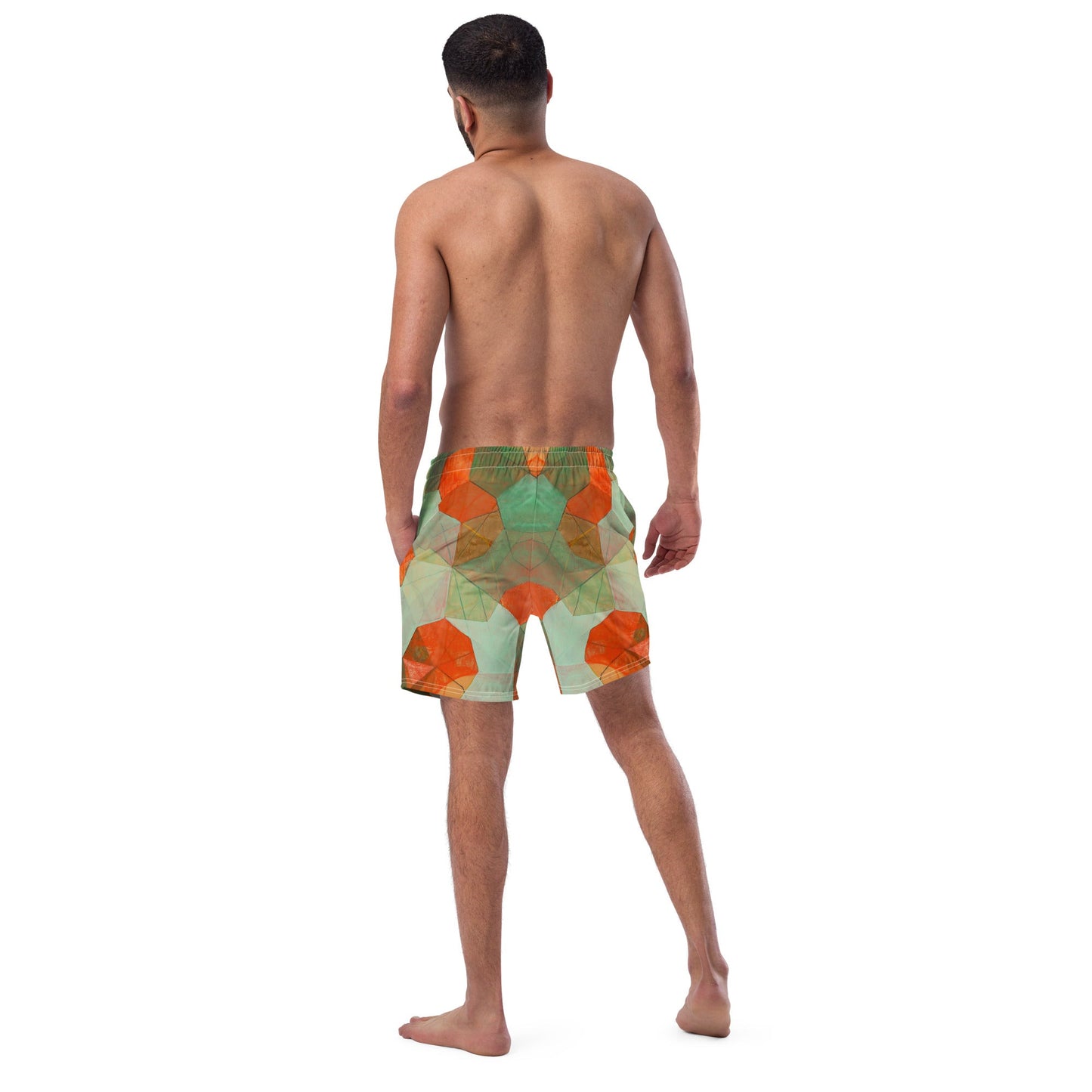 Back view of man wearing multi colored geometric print orange and green swim trunks.