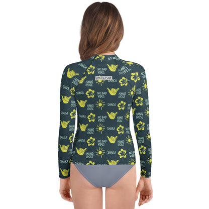 Back view of girl in dark blue rash guard with yellow designs of the sun, hibiscus flowers, hang loose hand sign, and the words hang loose, no bad vibes, and shaka.