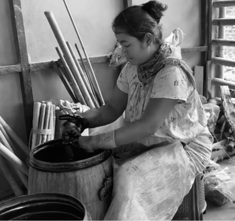 Woman sitting on stool dying natural silk material.