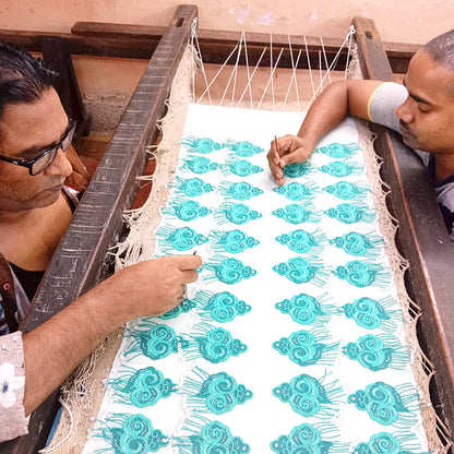 Artisans making light and dark green cloud earrings with tassels.