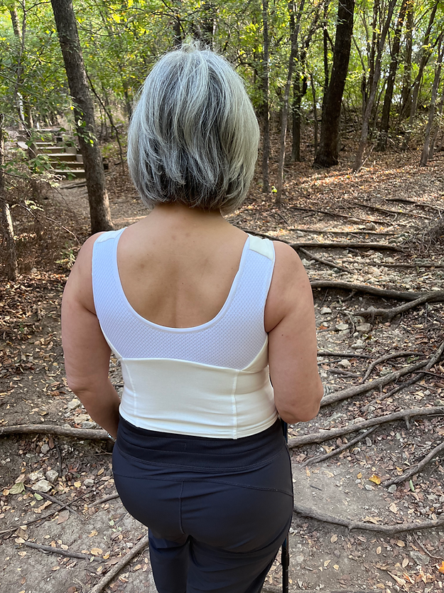 Back view of woman wearing white waist length crop top and black pants.