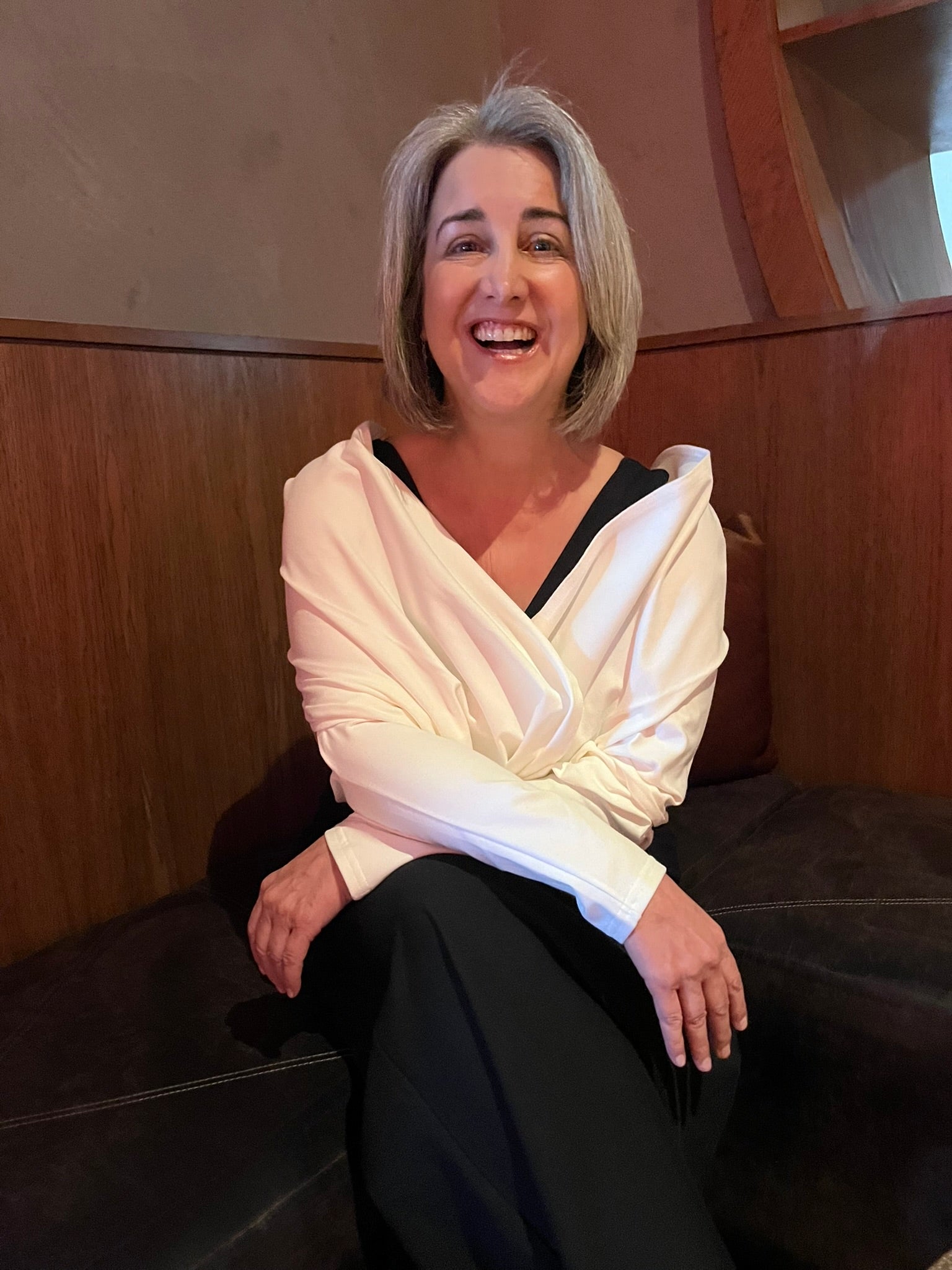 Woman with crossed arms, wearing a white wrap over a black shirt.