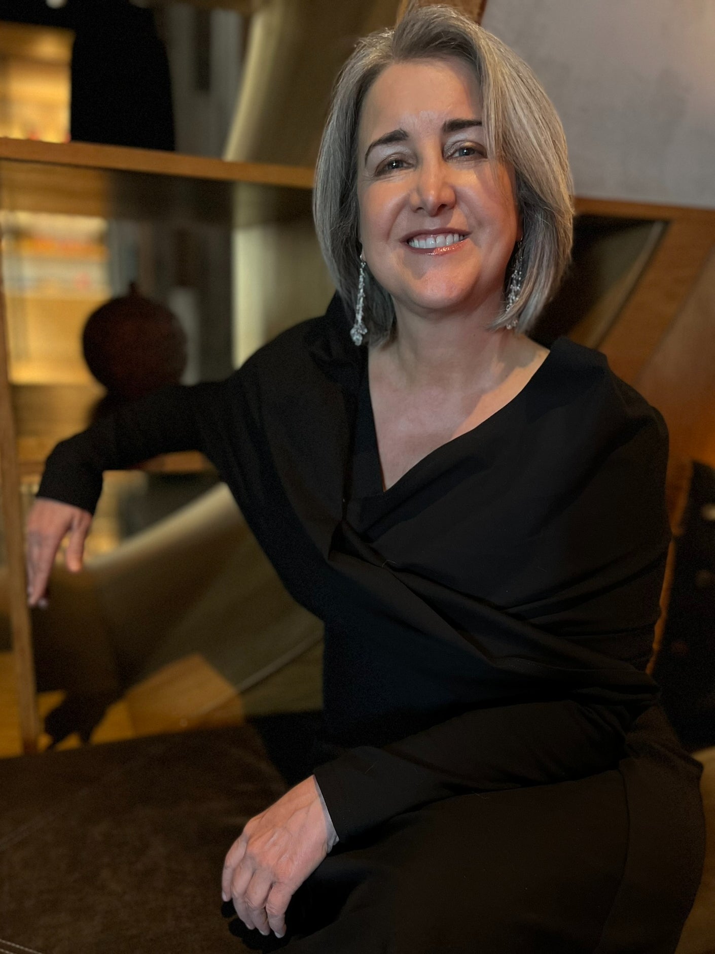 Woman sitting at desk wearing black wrap over a black shirt.