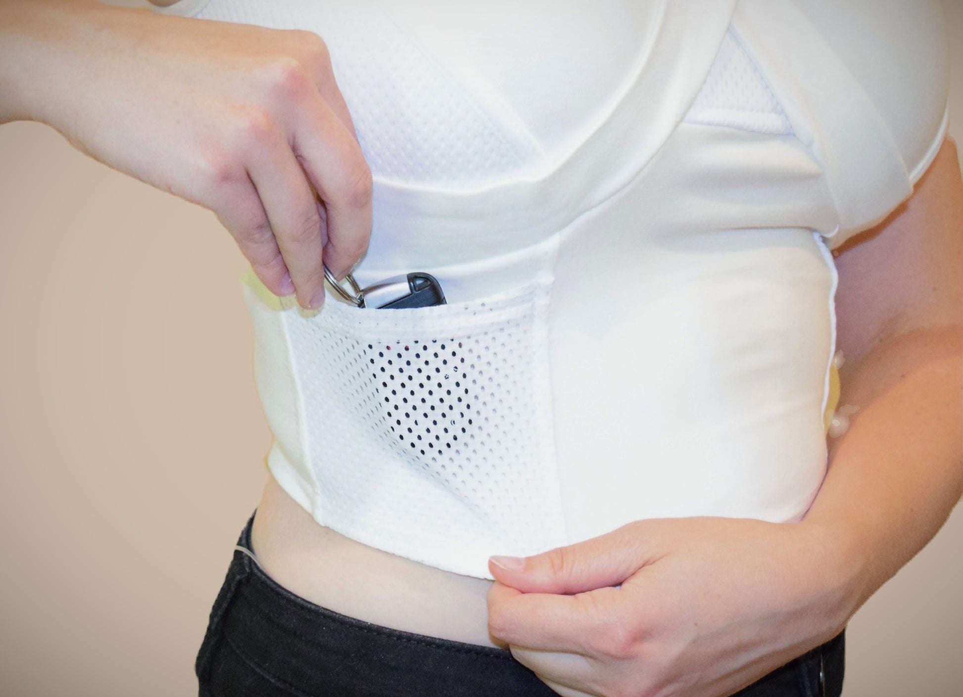 Closeup of mesh pocket of the white waist length crop top.