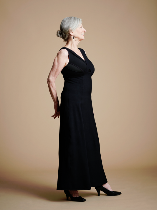Front right view of woman wearing long black dress with lay-flat v neck look.