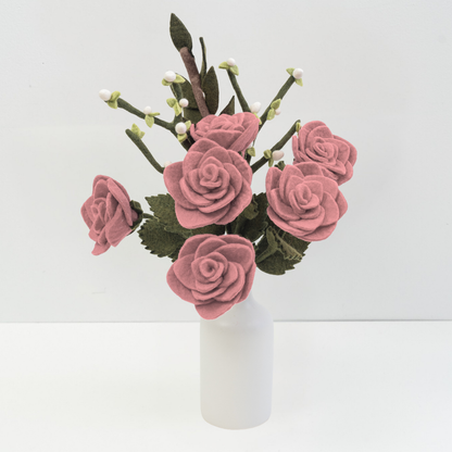 Felt flower bouquet of pink roses and white buds in a white vase with white background.