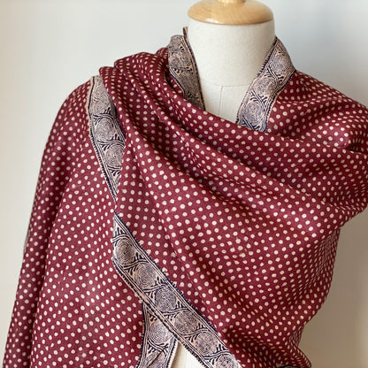 Manikin wrapped in red, natural, black stole with natural polka dots.