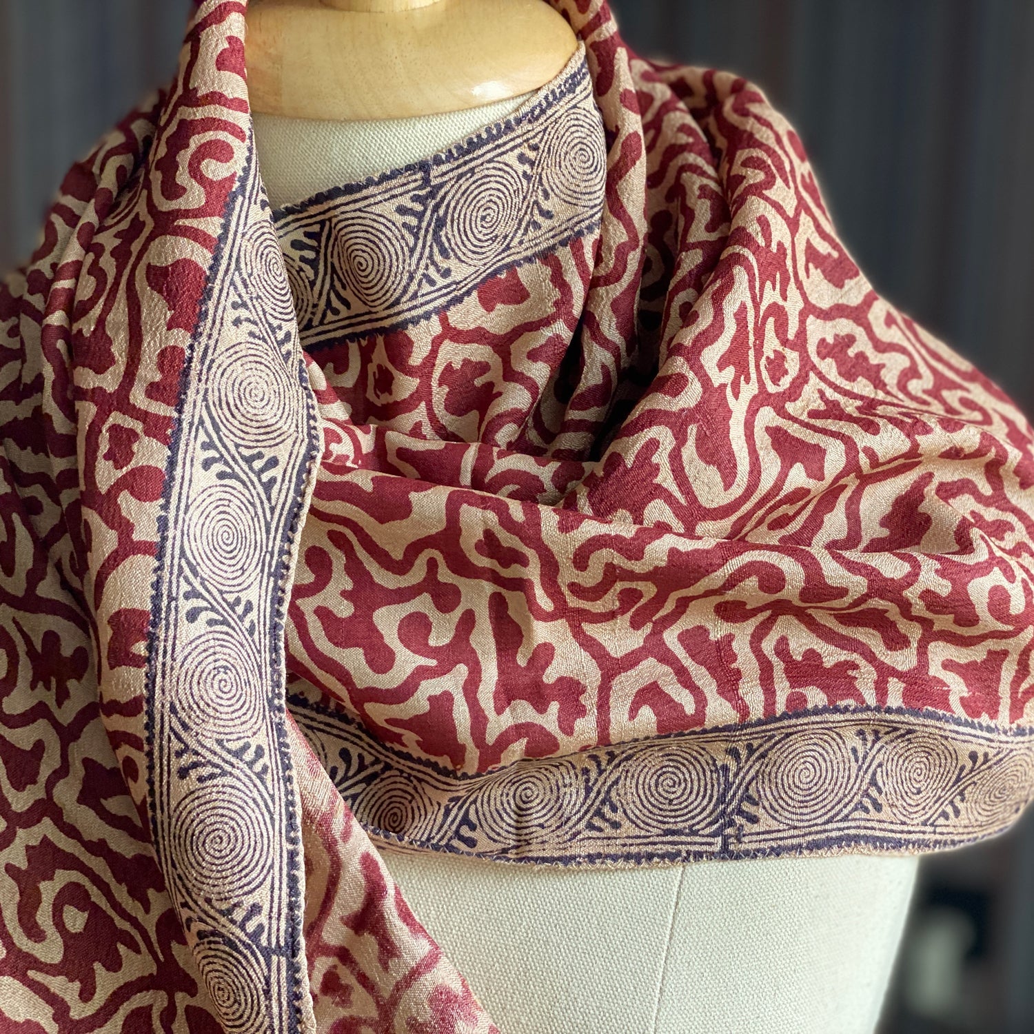 Red, natural, black silk stole wrapped loosely around a manikin.
