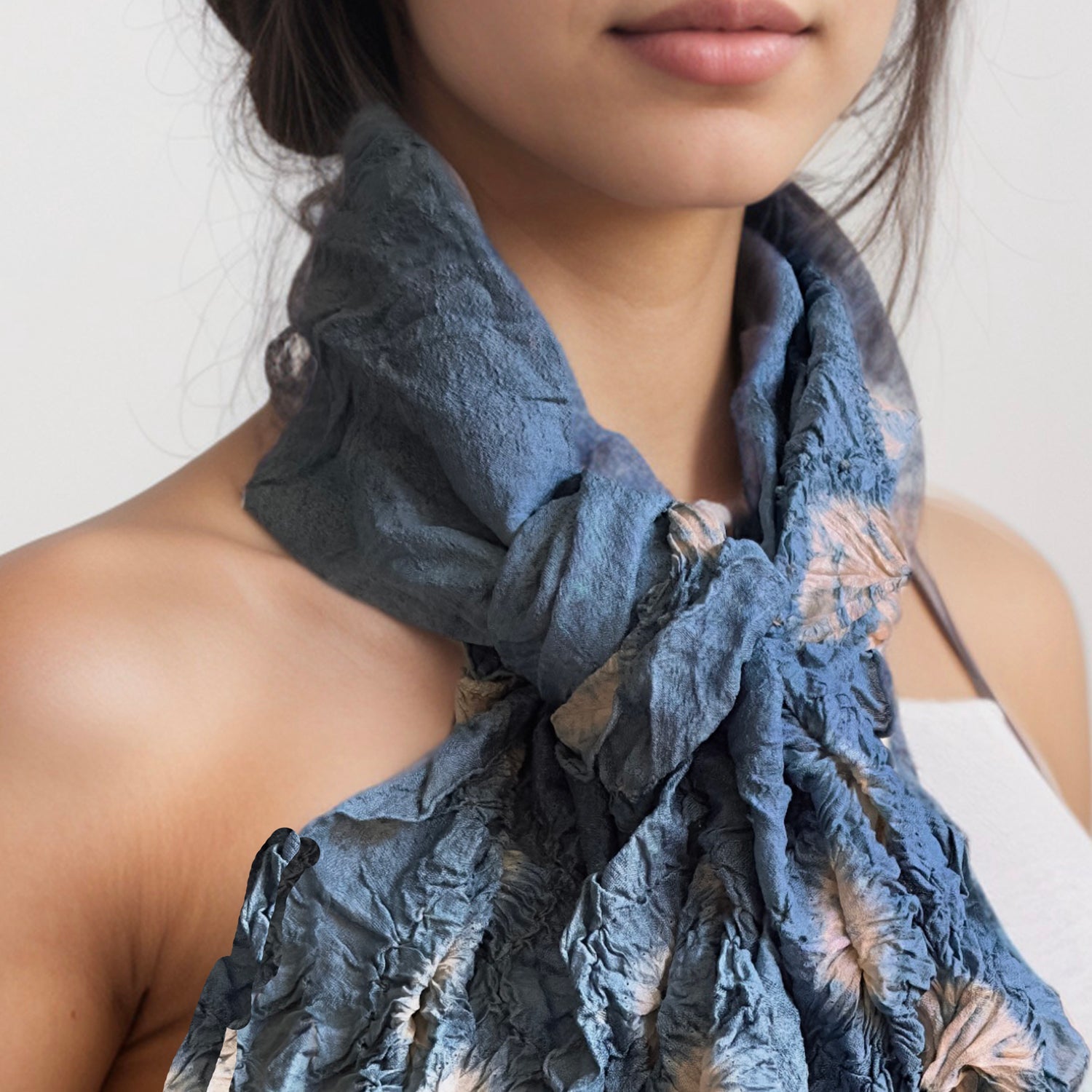 Closeup of tie died blue and natural silk scarf around woman's neck tied with a half knot.
