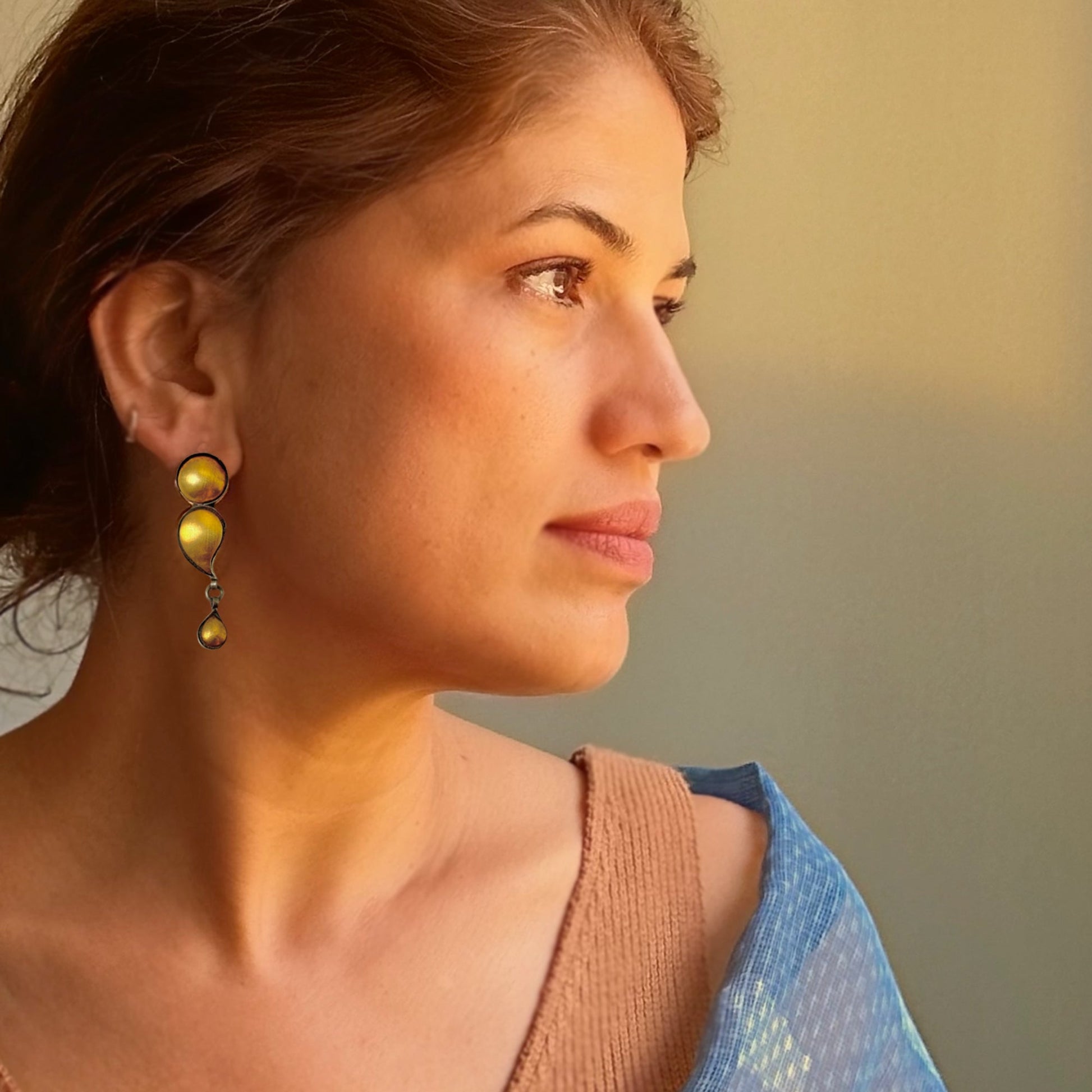 Right front view of woman wearing gold foil earrings with tribal design.