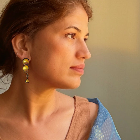 Right front view of woman wearing gold foil earrings with tribal design.