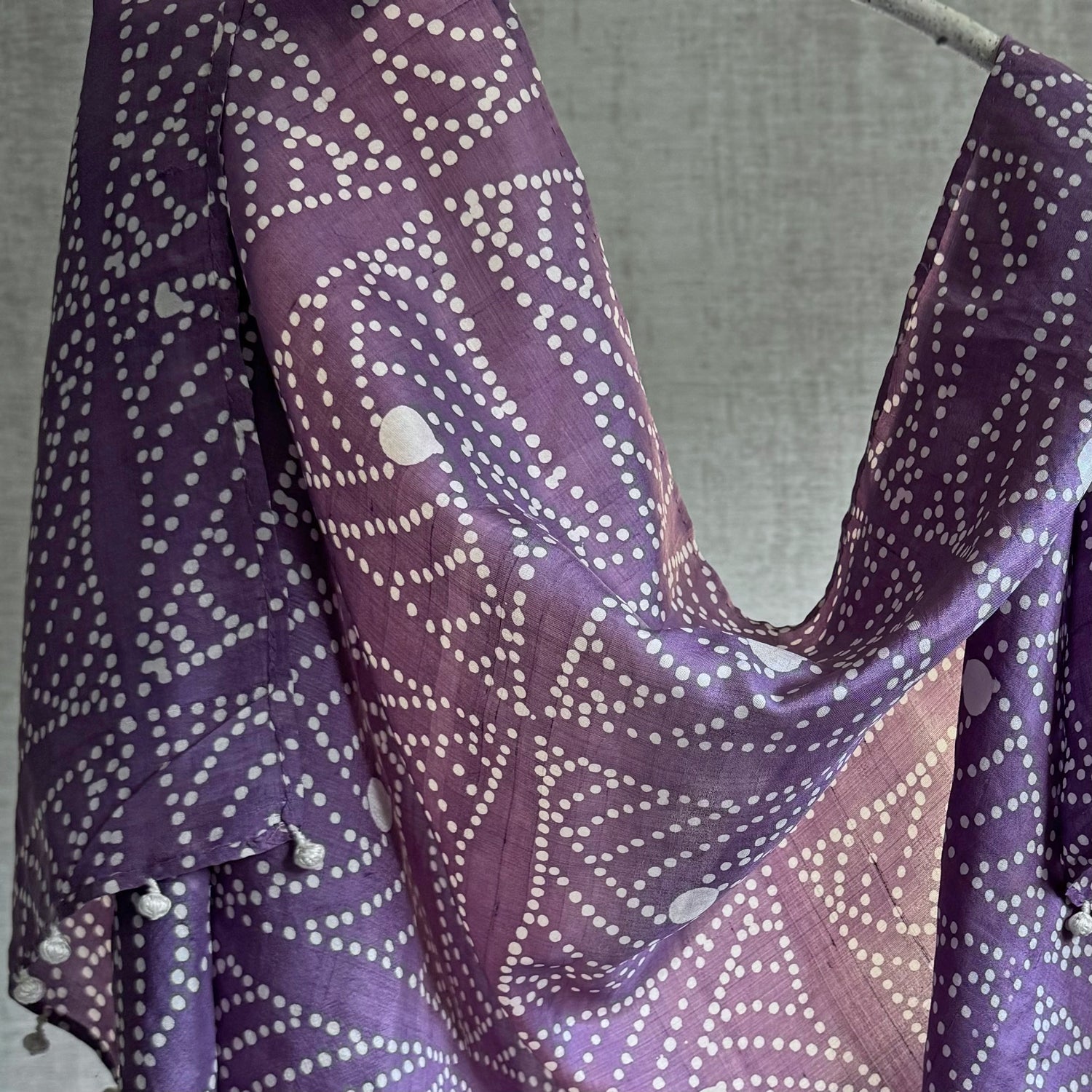 Closeup of purple and white batik scarf draped on branch.
