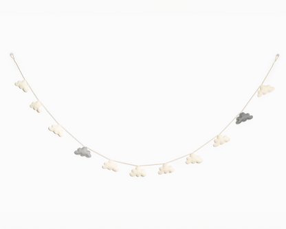 Grey and white felt cloud garland hanging on a white wall.