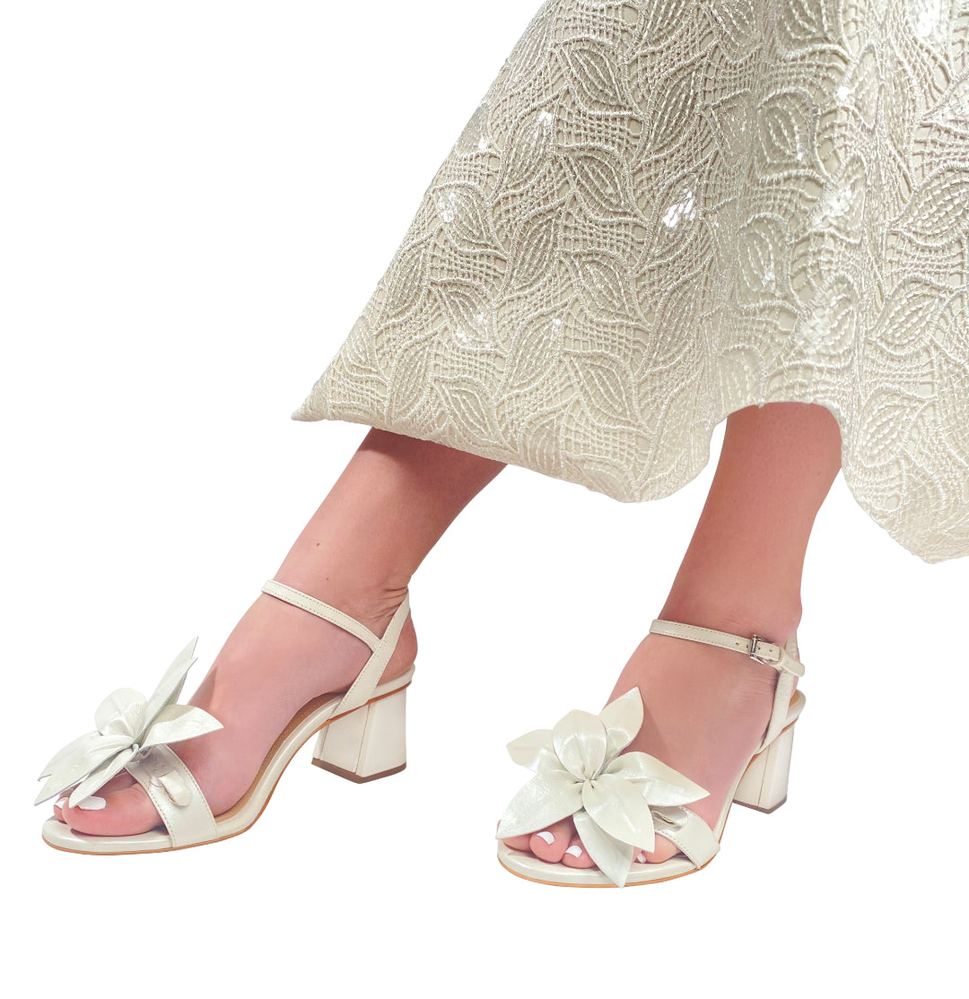 Closeup of woman's lower leg and dress, wearing  pearl sandal with pearl flower toe strap.