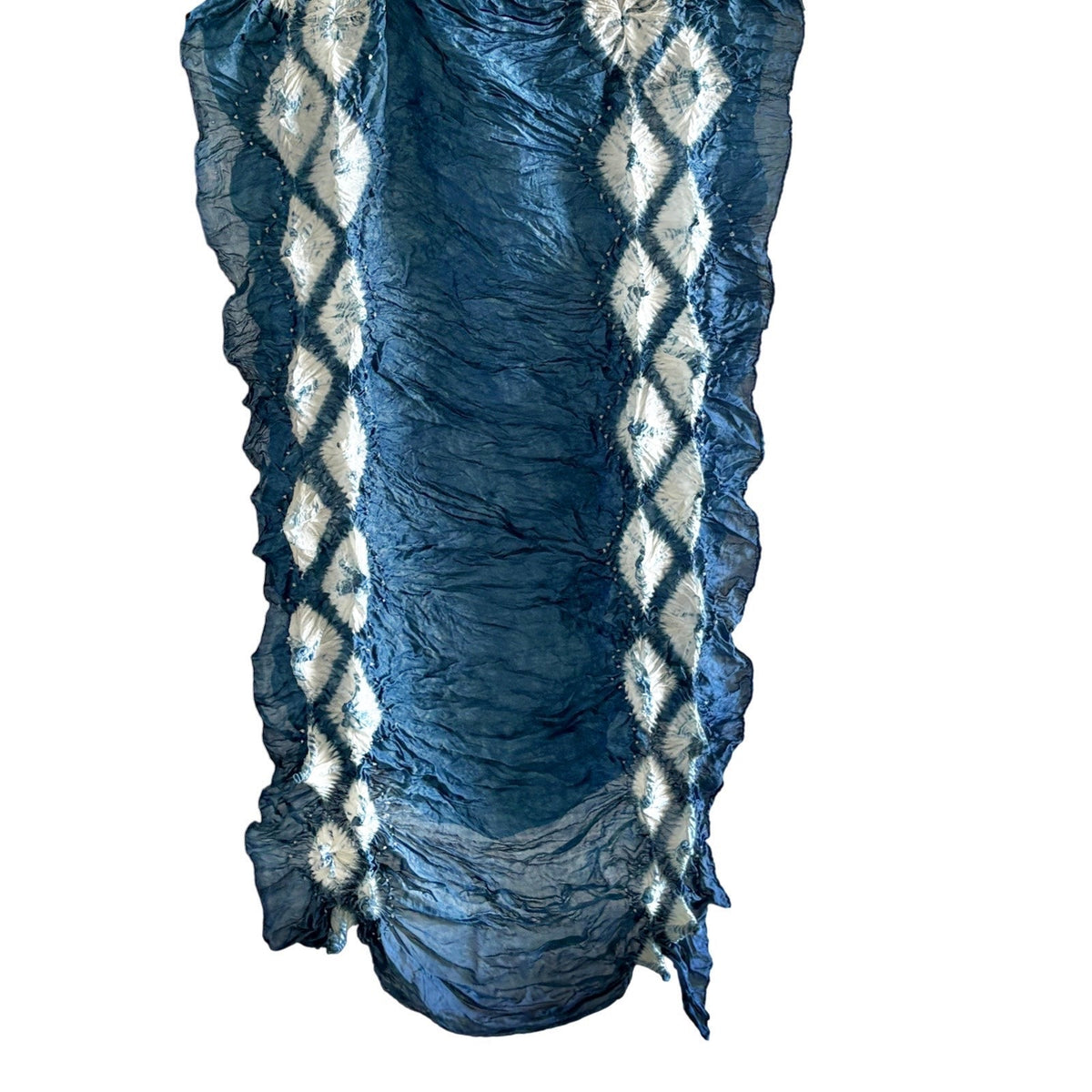 Natural indigo-dyed silk scarf in dark blue with white diamond shapes, hanging vertically on white background.