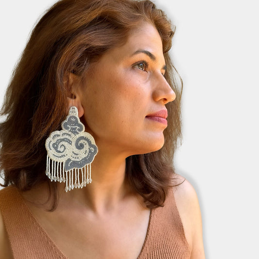 Right front view of woman wearing white and black cloud earrings with tassels.