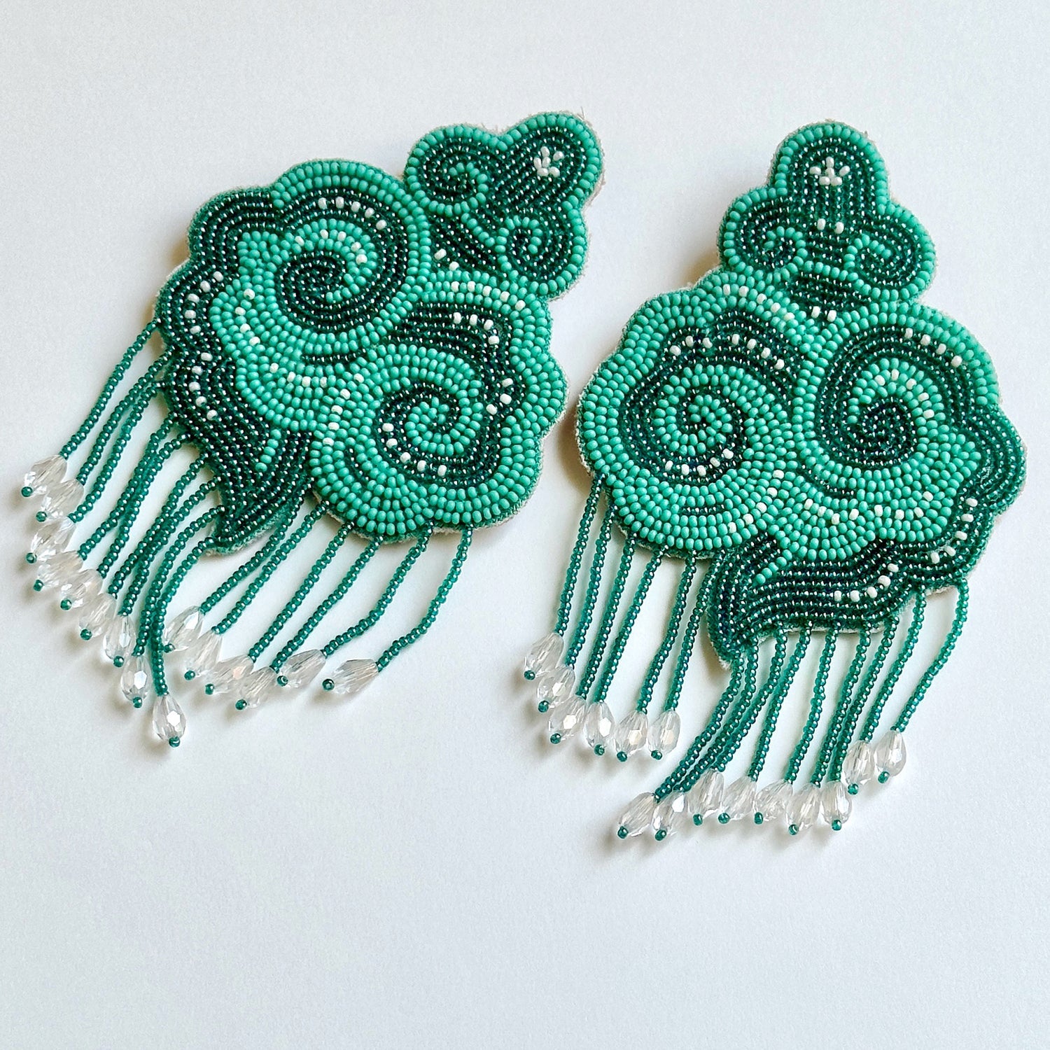 Pair of light and dark green cloud earrings with tassels.