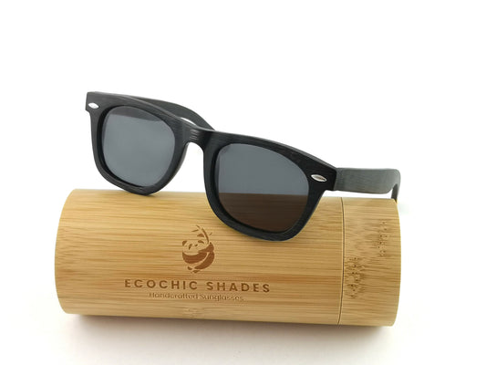 Bamboo wayfarer style sunglasses in black with black lenses on cylindrical bamboo case.