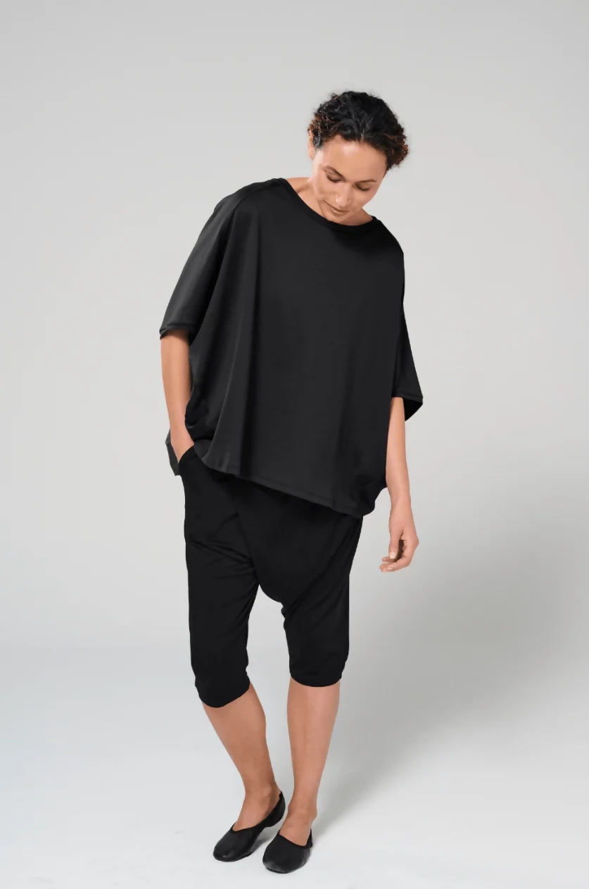 Woman wearing drapey black organic cotton top.