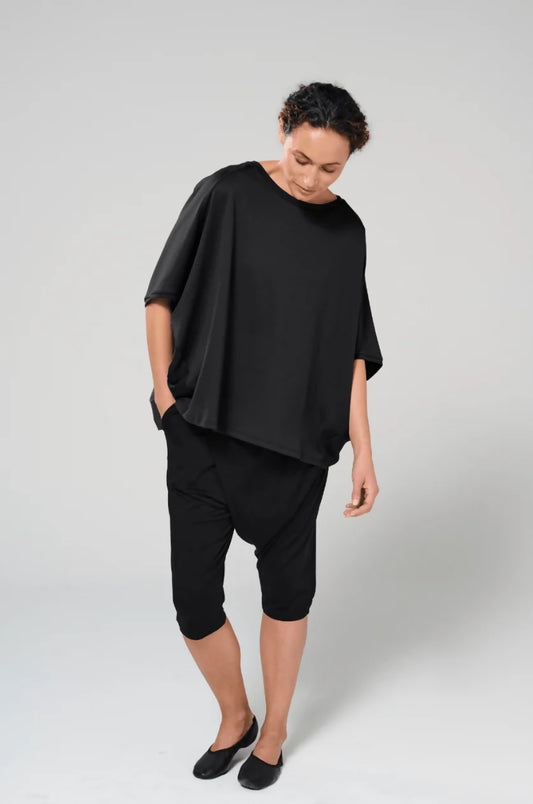 Woman wearing drapey black organic cotton top.