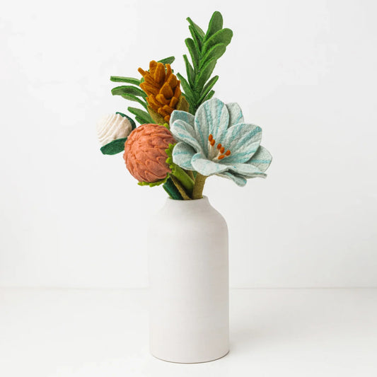Mustard, coral, green and blue felt floral arrangement in a white vase.