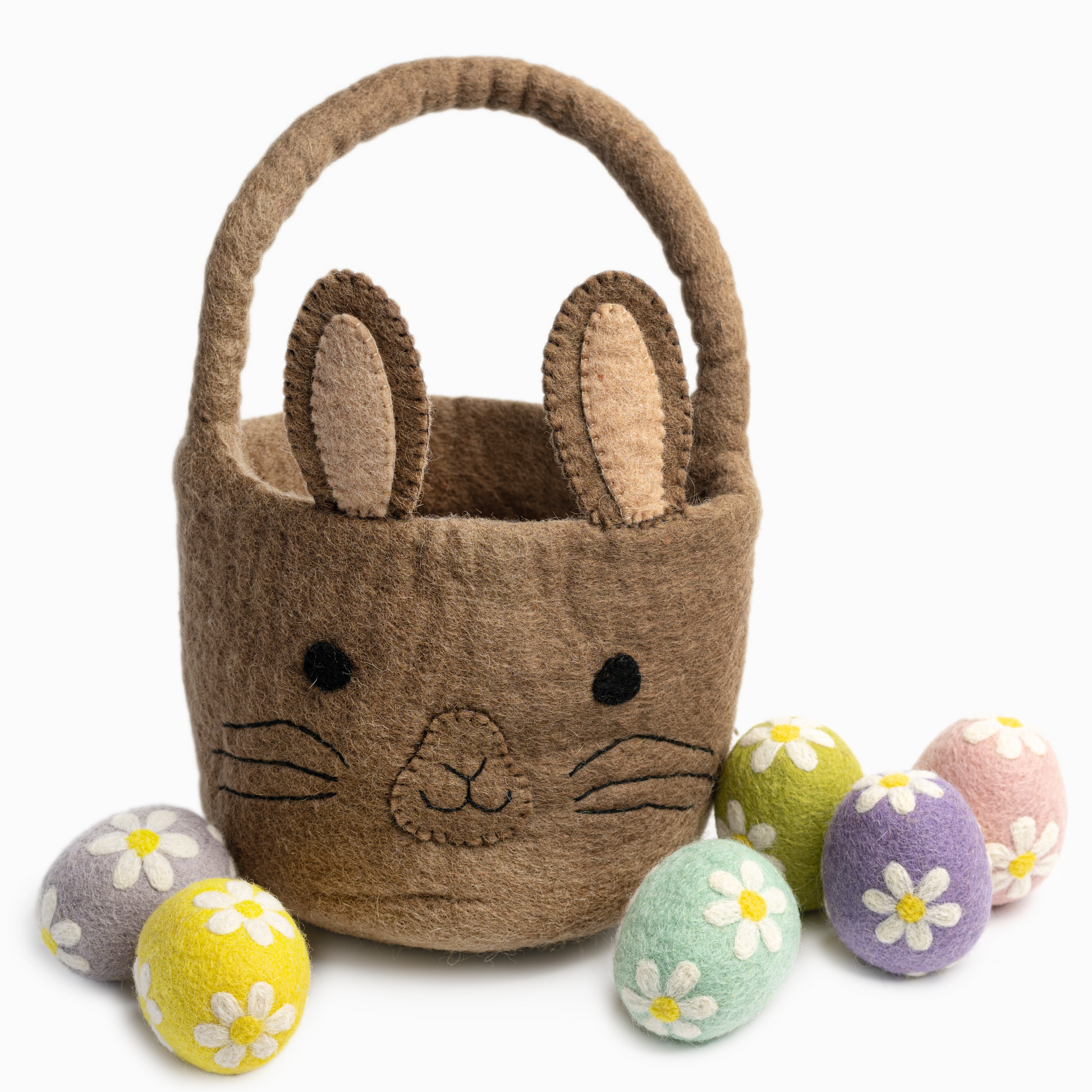 Felt easter eggs in pastel purple, blue, green, pink, and yellow colors decorated with white daisies scattered around brown bunny felt easter basket.