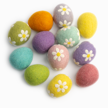 Felt easter eggs in pastel purple, blue, green, pink, and yellow colors decorated with white daisies scattered on white background.