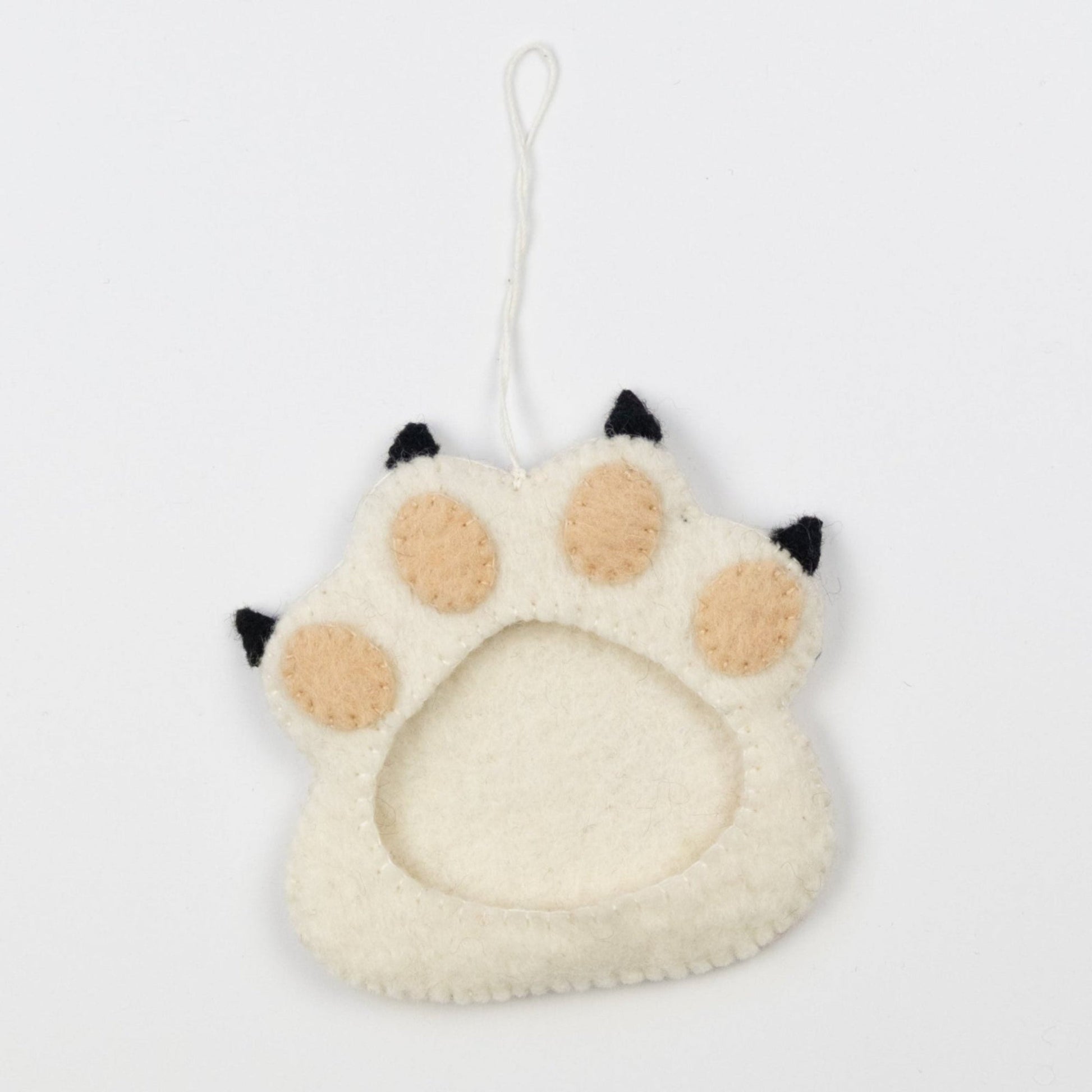 Felt ornament of a white paw print with a picture frame in the middle.