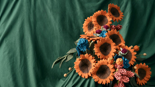 Fall/Halloween everlasting felt flower bouquet with yellow orange sunflowers, pumpkin accent stem, and various other flowers on greenbackground.