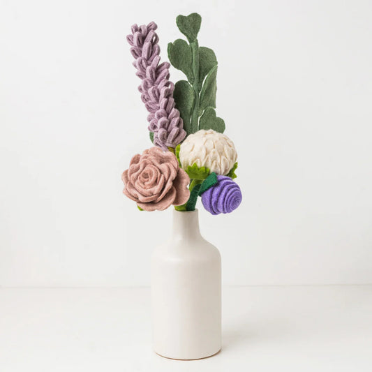 Purple, white, pink, and green felt floral arrangement in a white vase.
