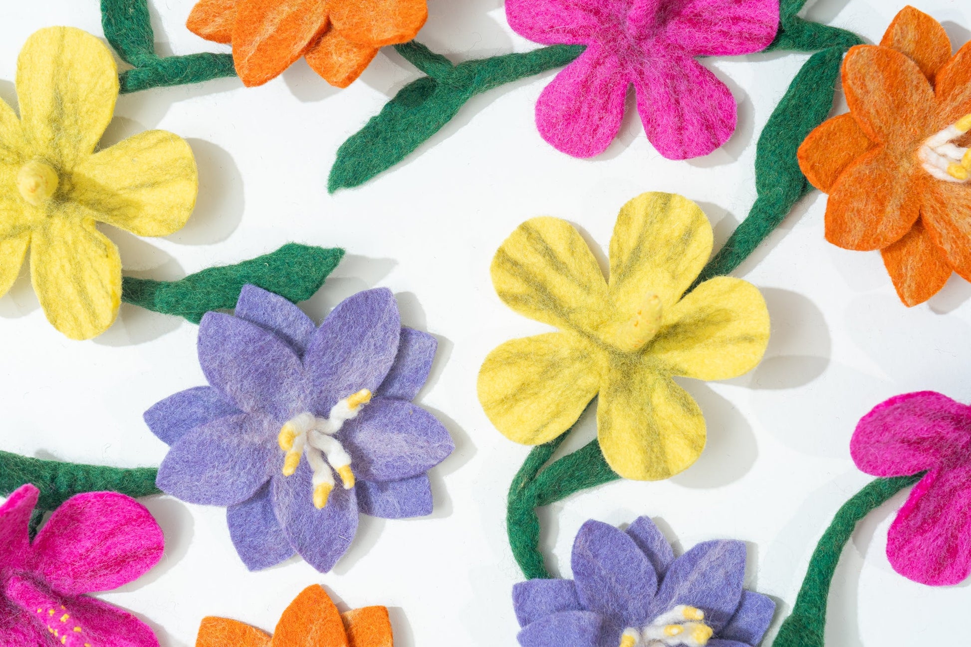 Colorful felt flowers on a white background handmade by women artisans in Nepal | Global Goods Partners