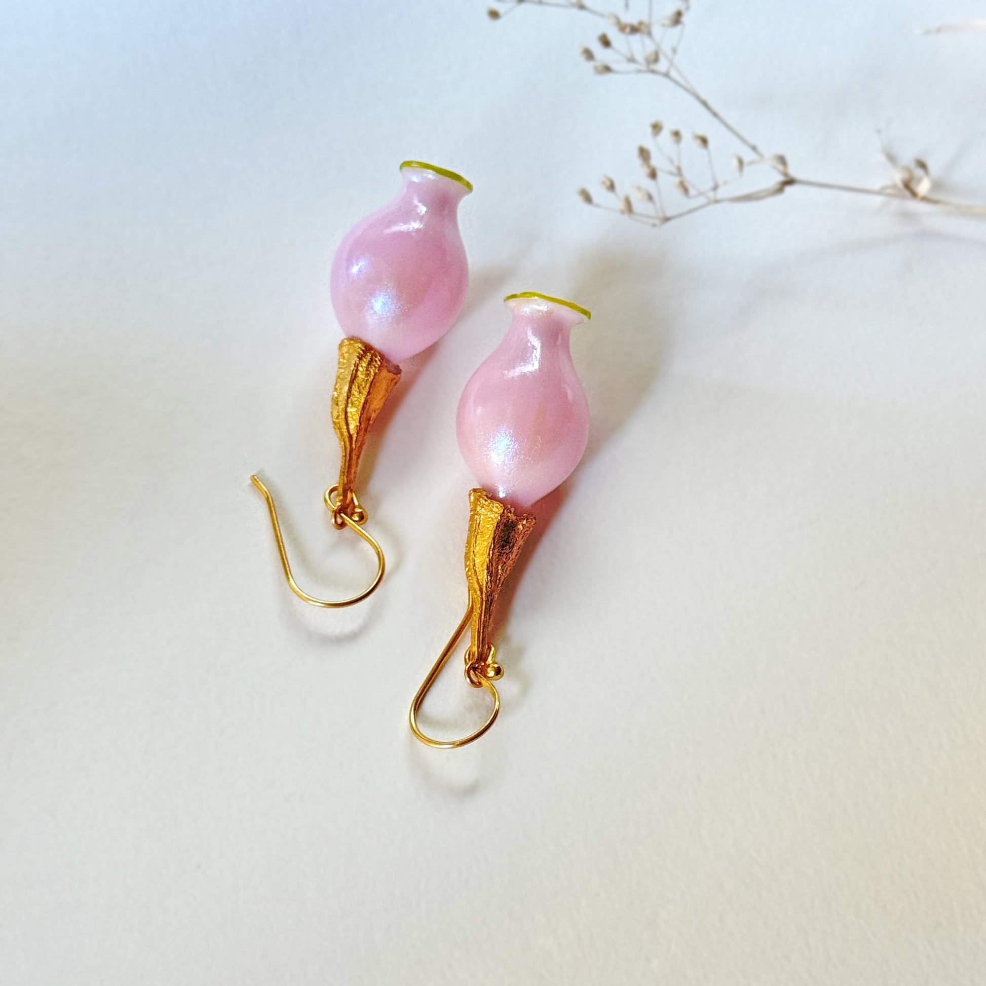 Pair of iridescent pink pod glass bud earrings with gold findings upside down.